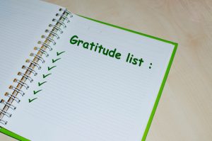 Gratitude list on open green agenda over wooden background